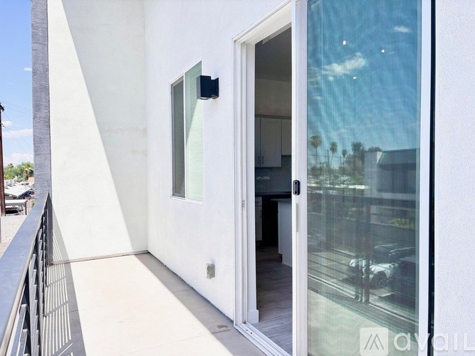 A balcony with a glass door leading to a room.