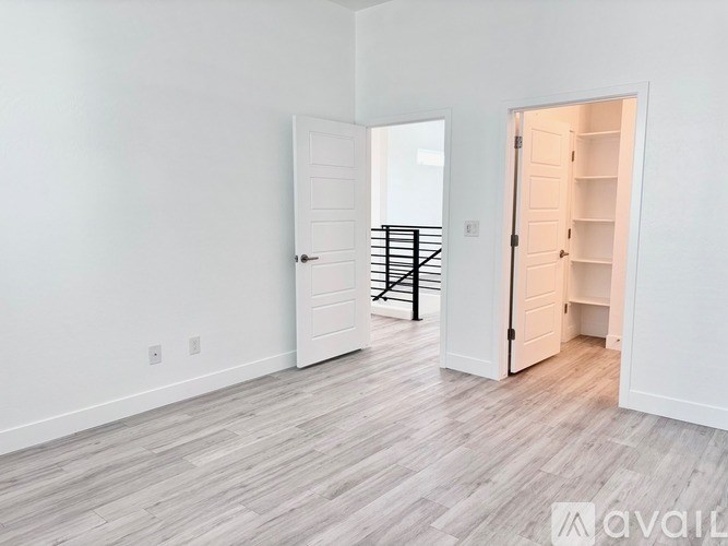 A room with a white door and a white wall with a wooden floor.