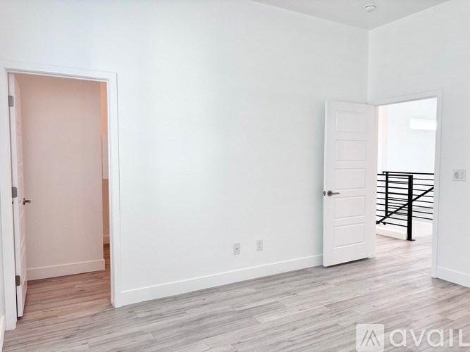 A room with a pink door and a white door with a balcony outside.