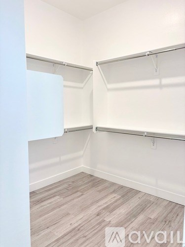 A white closet with shelves and a wooden floor.