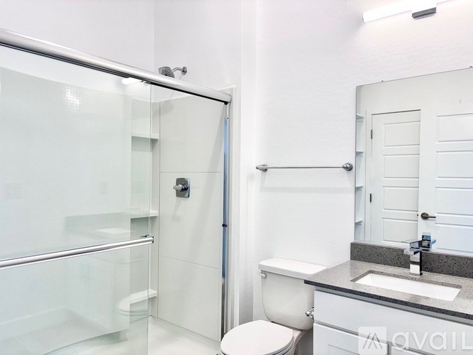 A white bathroom with a glass shower stall and a white toilet.