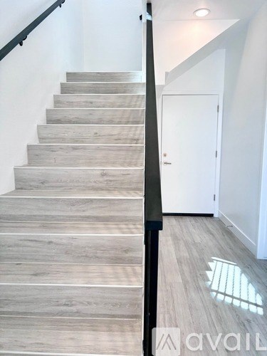 A set of stairs with a black railing and wooden steps.