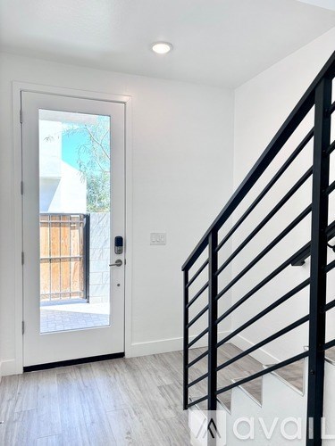 A white door with a glass window is on the left and a black staircase on the right.