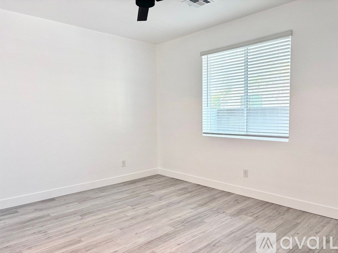 A room with a window covered by blinds and a wooden floor.