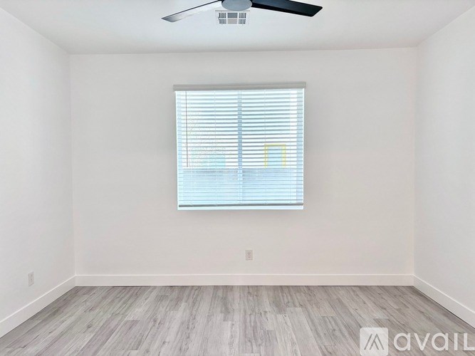 A room with a window covered by white blinds and a ceiling fan.