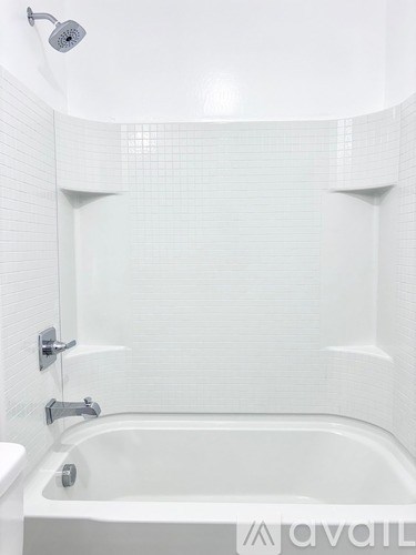 A white bathtub with a shower head above it.