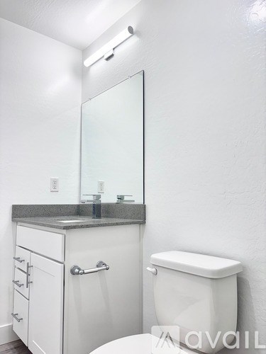 A white toilet sits next to a white cabinet with a mirror above it.