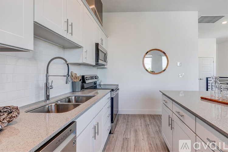A kitchen with white cabinets and a round mirror on the wall.