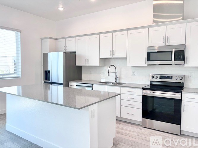 A modern kitchen with white cabinets and stainless steel appliances.