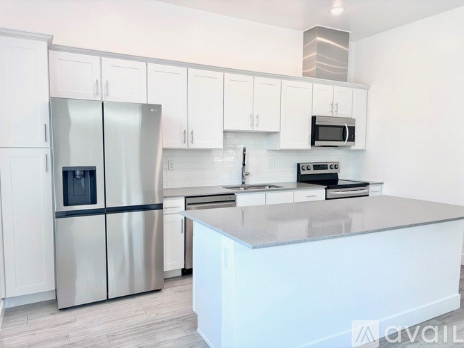 A kitchen with a stainless steel refrigerator, microwave, and oven.