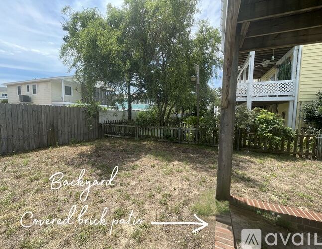 A backyard with a covered brick patio and a wooden fence.