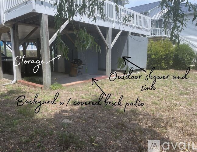 A backyard with a covered brick patio and an outdoor shower and sink.