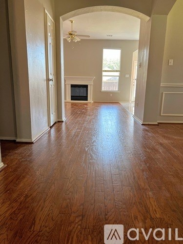 A hallway with wood flooring and a chandelier.