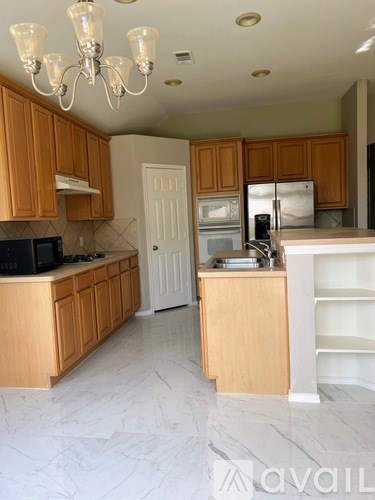 A kitchen with wooden cabinets and a chandelier.