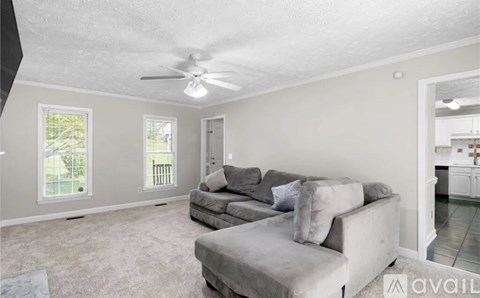 A living room with a grey couch and a ceiling fan.