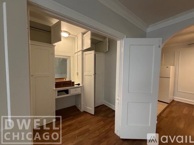 A room with wooden floors and white walls, with a door on the left and a closet on the right.