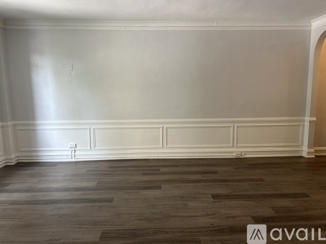 A room with wooden flooring and white walls.