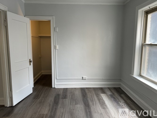 A room with a white door and a window with a grey wall.