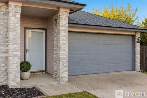 A house with a grey garage door and a black car parked in front.