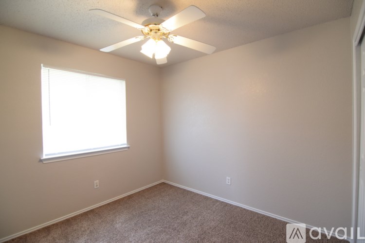A room with a ceiling fan and a window letting in light.