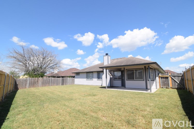 A house with a fence and a tree in the background.