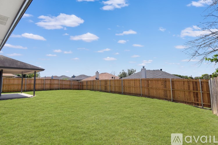 A backyard with a wooden fence and a covered patio area.