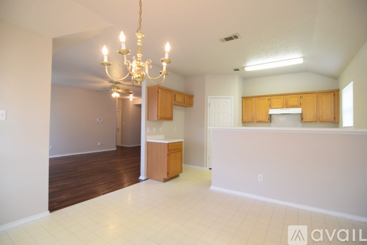 A large, empty room with a chandelier and a kitchenette.
