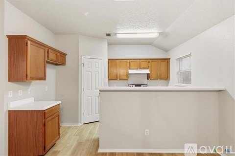 A large, empty room with a chandelier and a kitchenette.