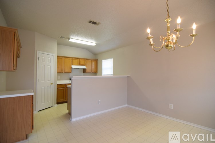A chandelier hangs over a kitchen island in a spacious room.