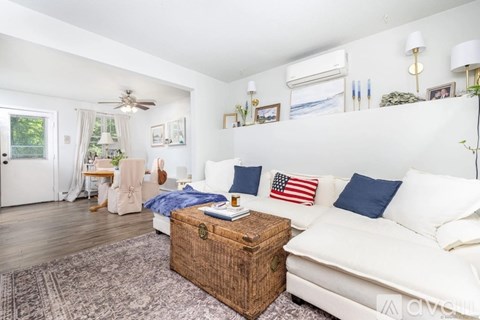 A living room with a white couch and a wooden box on the floor.