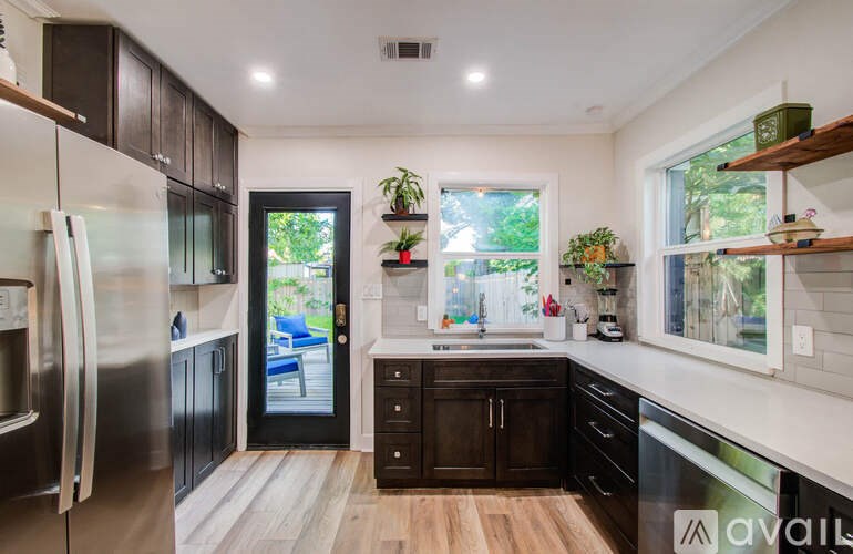 A kitchen with a refrigerator, sink, and wooden floors.