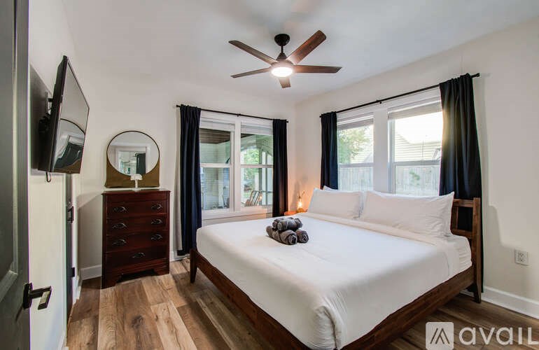 A bedroom with a large bed, a dresser, and a ceiling fan.