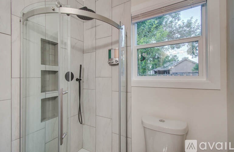 A bathroom with a glass shower stall and a toilet.
