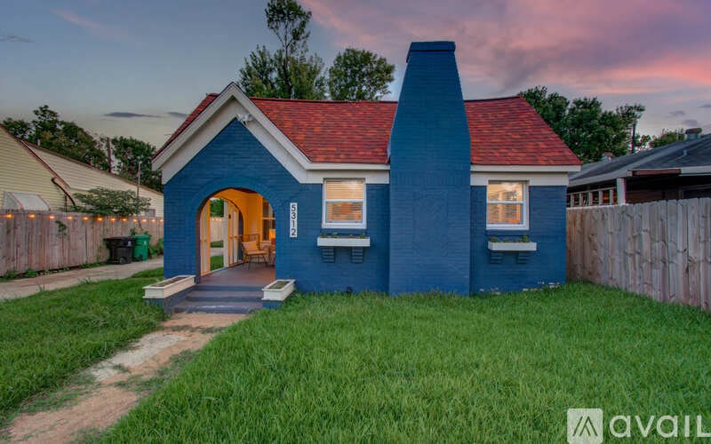 A blue house with a red roof and a chimney.