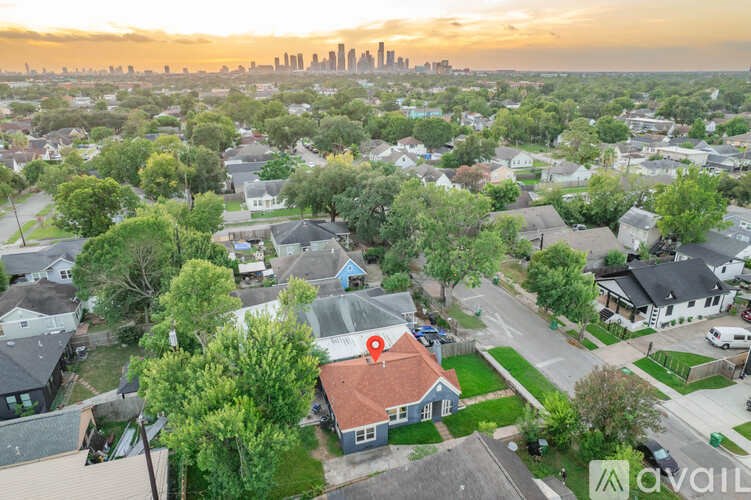 A house with a red roof is in the foreground of a suburban neighborhood.