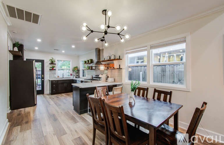 A kitchen with a table and chairs in the foreground and a refrigerator in the background.