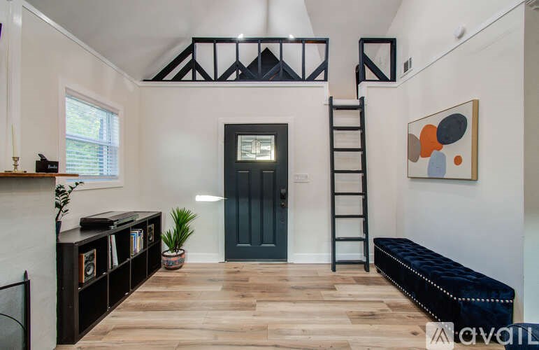 A room with a dark blue door, a wooden floor, and a painting on the wall.