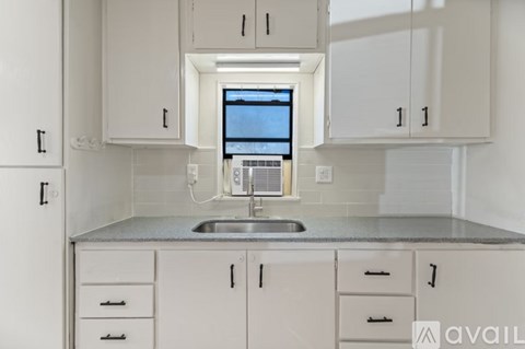 A kitchen with white cabinets and a window above the sink.