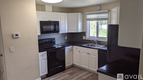 A kitchen with black countertops and white cabinets.