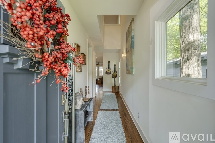 A hallway with a decorative garland on the left side and a carpeted floor.