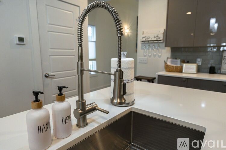 A bathroom sink with a chrome faucet and two bottles of soap labeled "hand soap" and "dish soap.".