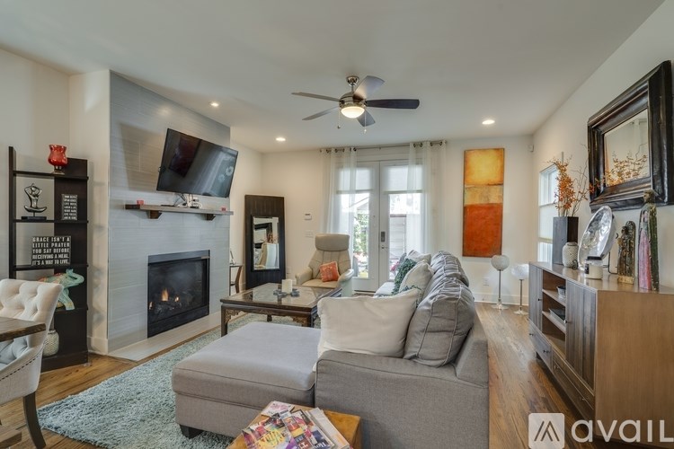 A living room with a grey couch, a fireplace, and a television on the wall.