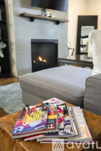 A stack of magazines on a coffee table in front of a fireplace.