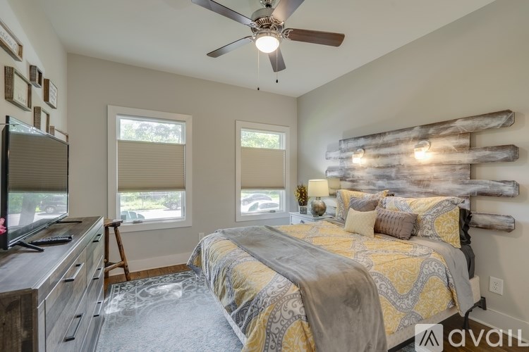 A bedroom with a bed, a television, and a ceiling fan.