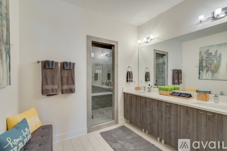 A bathroom with a grey couch and a mirror above a vanity.