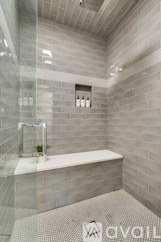 A modern bathroom with a glass shower enclosure and grey tiled walls.