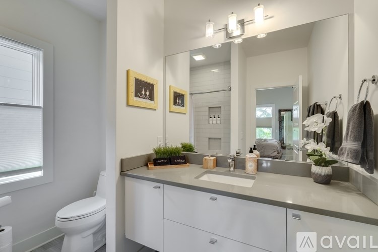 A bathroom with a white toilet, a white sink, and a large mirror.