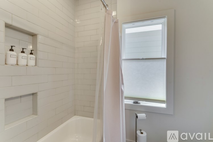 A white bathroom with a tub, shower, and a window.