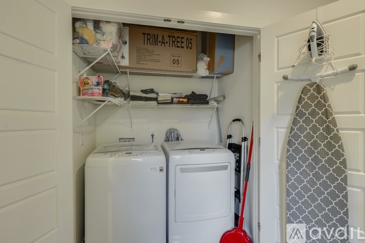 A small laundry room with a washer and dryer and a sign that says "TRIM-A-TREE 05 05".