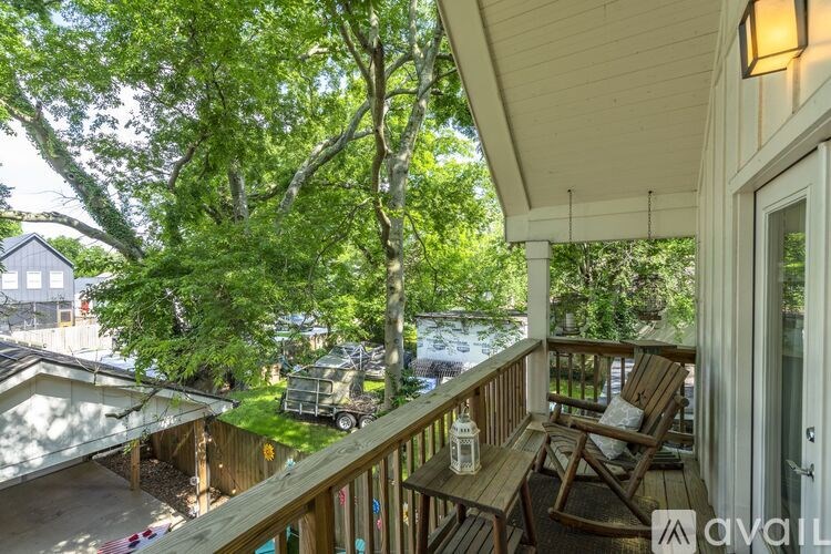 A balcony with chairs and a table is overlooking a yard.